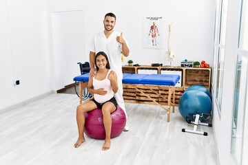 Fototapeta premium Young asian woman getting pregnancy class at physiotherapist clinic smiling happy and positive, thumb up doing excellent and approval sign