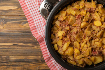 Braised pork with potatoes and onions on a brown wood. Composition with vegetables. Place to copy. Place for text. Fried potato recipe.