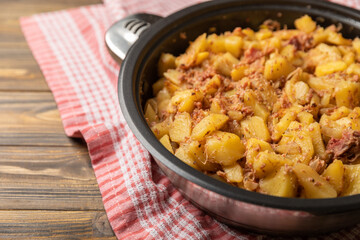 Braised pork with potatoes and onions on a brown wood. Composition with vegetables. Place to copy. Place for text. Fried potato recipe.