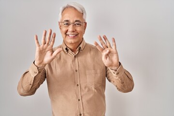 Hispanic senior man wearing glasses showing and pointing up with fingers number nine while smiling...
