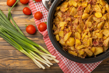 Braised pork with potatoes and onions on a brown wood. Composition with vegetables. Place to copy. Place for text. Fried potato recipe.