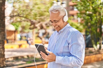 Fototapeta premium Senior man smiling confident watching video on touchpad at park