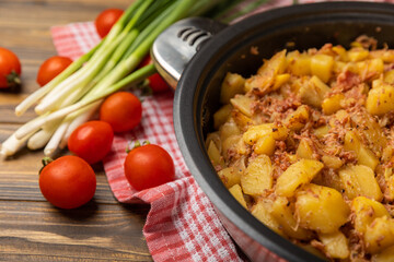 Braised pork with potatoes and onions on a brown wood. Composition with vegetables. Place to copy. Place for text. Fried potato recipe.