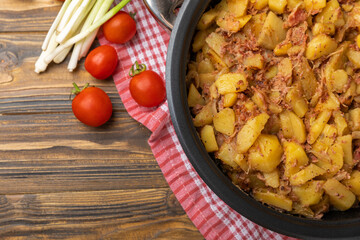 Braised pork with potatoes and onions on a brown wood. Composition with vegetables. Place to copy. Place for text. Fried potato recipe.