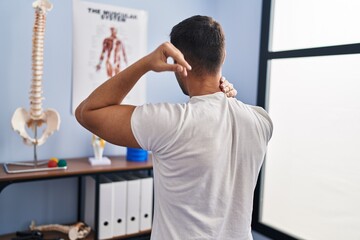 Fototapeta premium Young hispanic man injured physiotherapy patient suffering for neck ache at rehab clinic