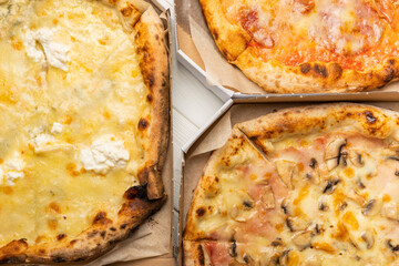 Delicious hot and fragrant pizza diabla with piperoni, cheese and vegetable pizza with mushrooms. Pizza in boxes. Pizza delivery. Composition on black texture background. Copy space. Italian food. 