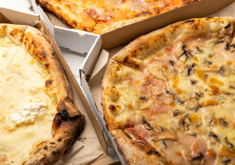 Delicious hot and fragrant pizza diabla with piperoni, cheese and vegetable pizza with mushrooms. Pizza in boxes. Pizza delivery. Composition on black texture background. Copy space. Italian food. 