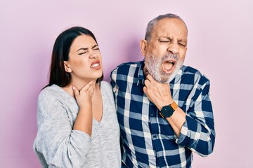 Hispanic father and daughter wearing casual clothes touching painful neck, sore throat for flu, clod and infection