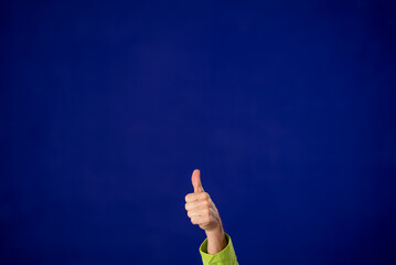 Arm with thumbs up isolated on solid purple background studio portrait. People lifestyle concept....