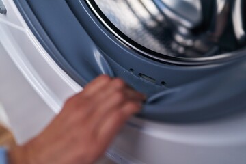 Young woman opening washing machine at laundry room