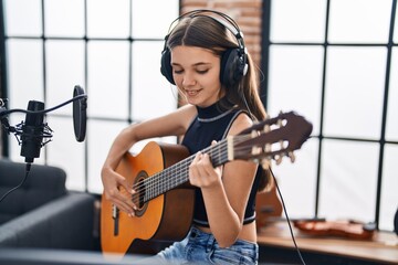 Fototapeta na wymiar Adorable girl musician singing song playing classical guitar at music studio