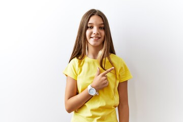 Young brunette teenager standing together over isolated background cheerful with a smile on face pointing with hand and finger up to the side with happy and natural expression