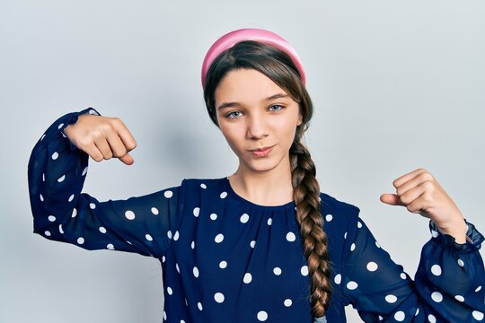 Young brunette girl wearing elegant look showing arms muscles smiling proud. fitness concept.