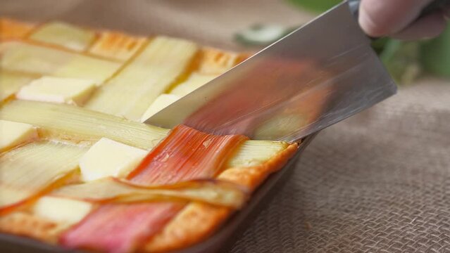 The chef cuts a freshly baked rhubarb pie with a knife, the idea of making traditional Siberian pies from seasonal products, live footage, 4k video.