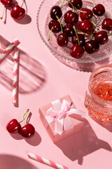 Festive flat lay with cherries drinks and a gift box, all in pink color