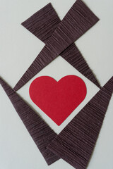 red paper heart and brown paper triangles arranged on a paper background