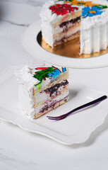 Piece of blueberry cake with white cream on white table