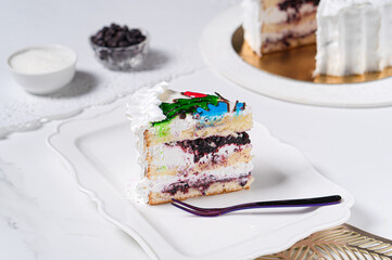 Piece of blueberry cake with white cream on white table