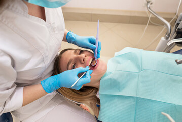 Dentist-hygienist conducts a teeth cleaning procedure for a girl in a dental clinic. Removal of tartar.