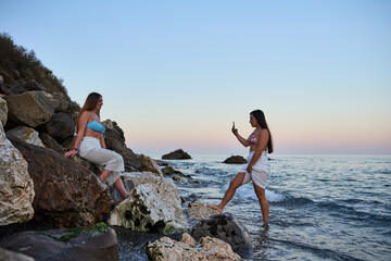 young girl making a photo of her friends with her smartphone at the beach