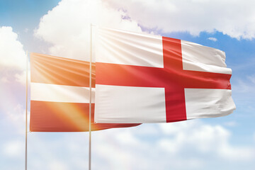 Sunny blue sky and flags of england and latvia