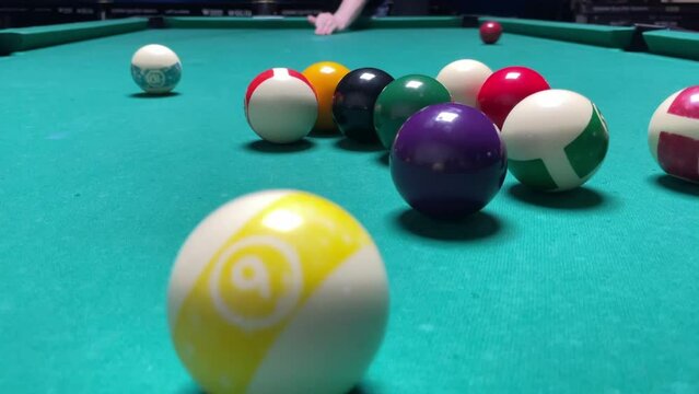 pool,player on a billiard table breaks a triangle with balls, starts the game