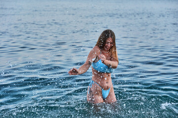 young blonde with freckles playing with the water splashing on her body