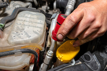 The mechanic puts the quick-release fastener in red on the valve from the air conditioning system...