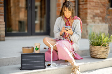 Woman charge phone from a portable solar panel