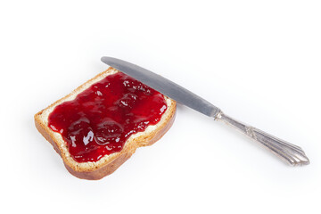a piece of white bread with strawberry jam and a silver knife, isolated on white background