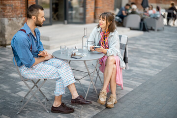 Stylish couple of colleagues have a conversation while sitting at cafe terrace