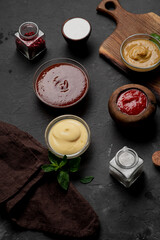 Products for cooking pizza and salad on a dark background. Fresh vegetables, sauces and herbs with spices.