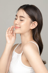 Beautiful young Asian woman model touch her face with perfect clean fresh skin on grey background....