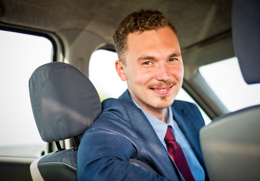 Businessman car salesman driver behind the wheel looking into camera and smiling