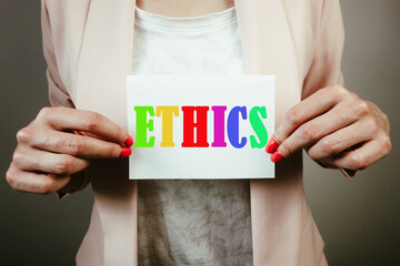 Businesswoman holding sheet of paper with word ethics. Business integrity and moral concept