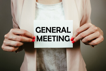 Business woman holding note with text general meeting. AGM concept