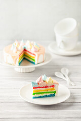 Delicious rainbow cake on plate on table on light wooden background