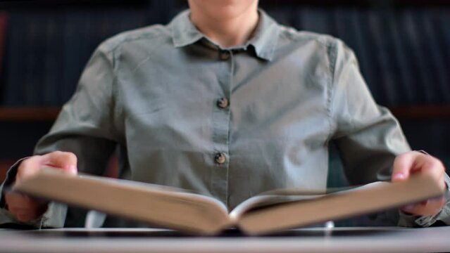 Unrecognizable academic woman open vintage paper book antique text publication at library desk