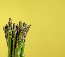 Bunch of fresh green asparagus on a yellow background. Copy space.