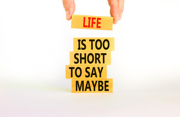 Life is short for maybe symbol. Concept words Life is too short to say maybe on wooden blocks on a beautiful white table white background. Businessman hand. Business motivational life maybe concept.