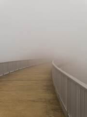 Geländer einer Brücke verliert sich im Nebel