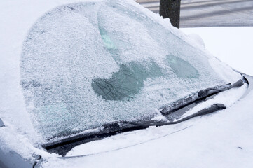 the snow falls on the car's glass at the beginning of winter