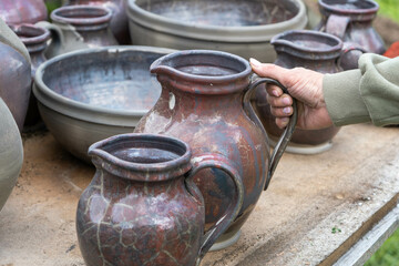Naklejka premium fired earthenware removed from the kiln. The woman looks at the outcome. Mugs, pots, plates and everything else beautiful and useful. Latvian national cultural heritage