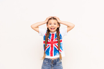 A little girl in a T-shirt with a British flag clutched her head. English courses for schoolchildren.