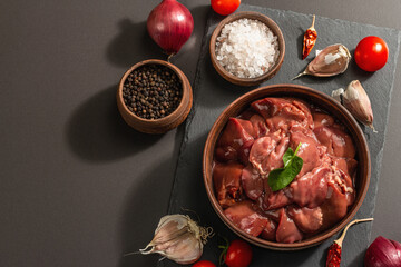 Raw chicken liver in a bowl. Fresh food ingredient and spices, trendy hard light, dark shadow