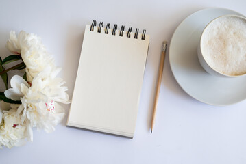 Top view of notebook with white empty page White peonies and Feminine home office mock up with...