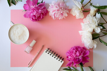 Stylish workspace with cup coffee, paper, laptop and pink peony flowers. Woman working table. Top view, flat lay, copy space.Pink peonies bouquet. Top view feminine background.Spring summer background