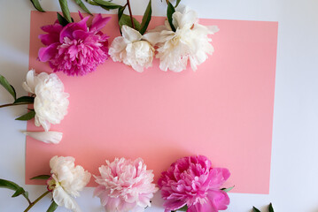 Stylish workspace with cup coffee, paper, laptop and pink peony flowers. Woman working table. Top view, flat lay, copy space.Pink peonies bouquet. Top view feminine background.Spring summer background