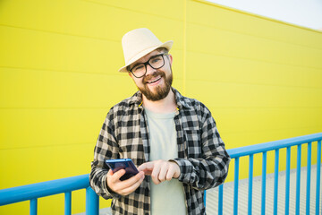 Bearded hipster guy in glasses using smartphone technology for making online booking and banking...