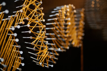 panel string art, yellow threads on nails close-up